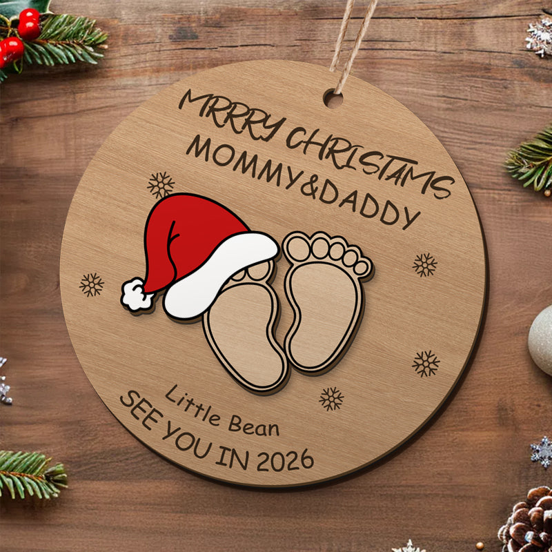 Merry Christmas baby footprint ornament for Mommy & Daddy, featuring Santa hat and "See You in 2026". Personalized holiday decor and pregnancy announcement gift, customizable with details.