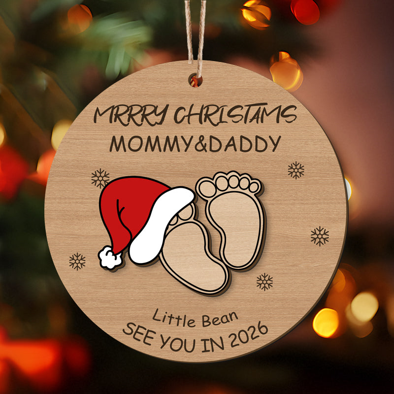 Personalized Christmas ornament with baby footprints, Santa hat, "Merry Christmas Mommy & Daddy", and "See You in 2026". Unique holiday gift for expecting parents