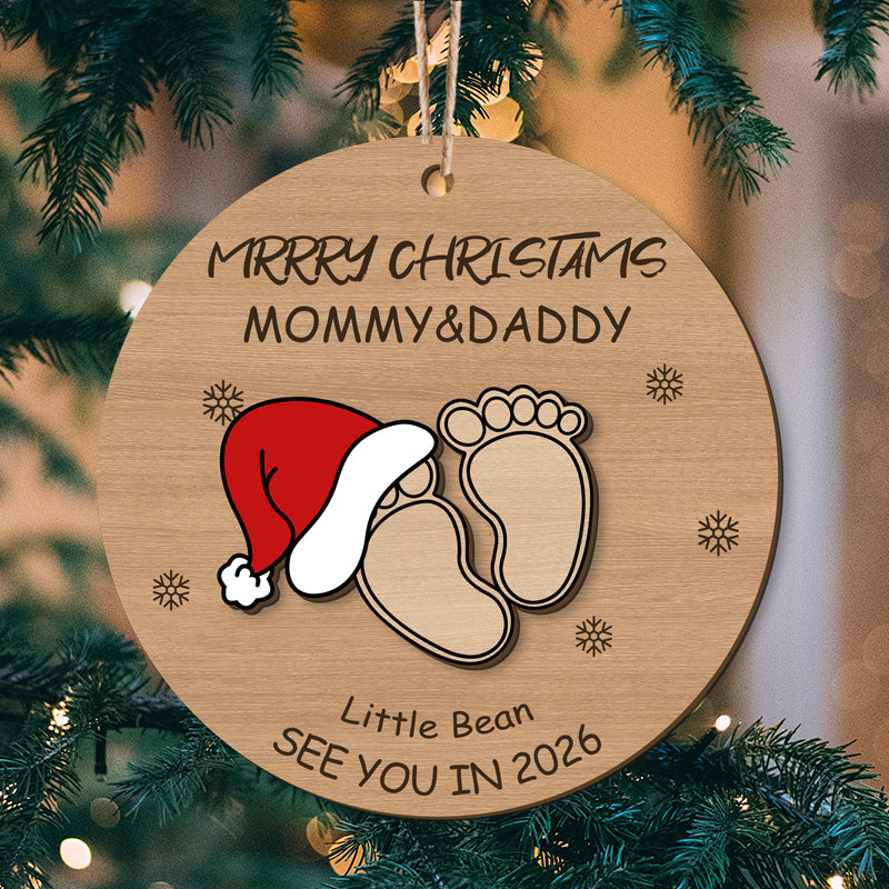 Custom baby footprint Christmas ornament with Santa hat, "Merry Christmas Mommy & Daddy", and "See You in 2026". Perfect personalized holiday keepsake for new parents, customizable with names and year.