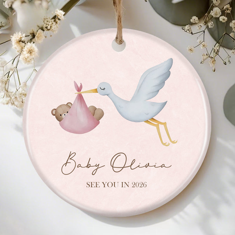 Custom stork and baby bear ornament for pregnancy announcement, featuring "See You in 2026" and personalized baby name space. Perfect keepsake for expecting parents, soft pink design with charming illustrations.