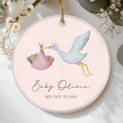Custom stork and baby bear ornament for pregnancy announcement, featuring "See You in 2026" and personalized baby name space. Perfect keepsake for expecting parents, soft pink design with charming illustrations.