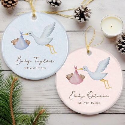 Custom ornament featuring stork delivering baby bear, "See You in 2026" message. Soft pink design, ideal for expecting parents as a personalized pregnancy announcement or holiday keepsake.